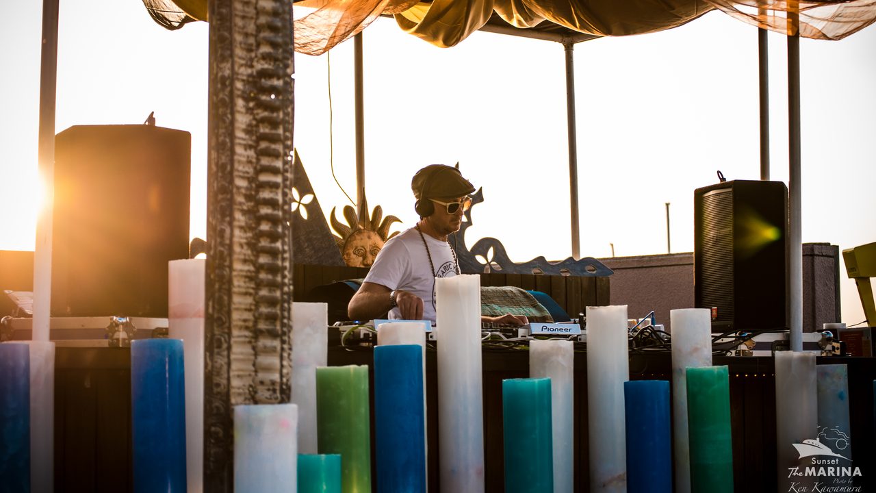 Chris Coco DJing at sunset, the sea and sky behind the decks